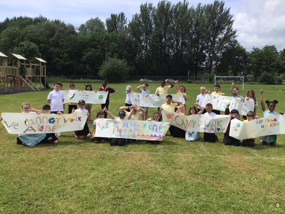 A group of children holding posters with we cannot walk alone written on them