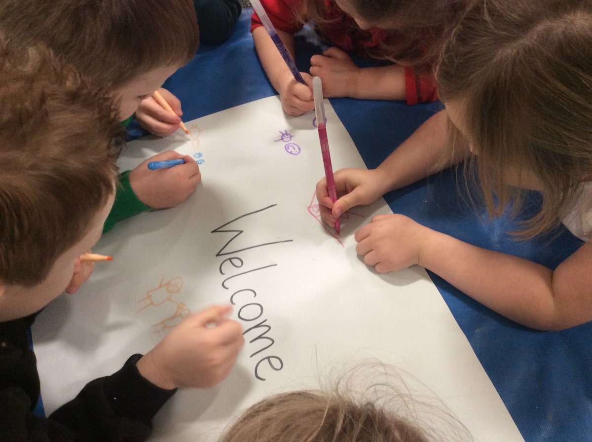 A group of children writing the word welcome on a piece of paper